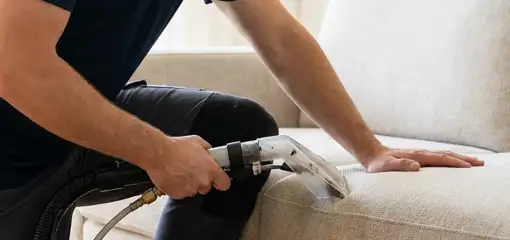 Professional upholstery cleaner deep-cleaning a fabric sofa with a handheld extraction tool, Wilmington, NC.